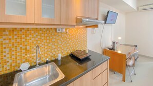 Una cocina moderna con un lavamanos de acero inoxidable, armarios de madera, salpicadero de azulejos y un pequeño escritorio con silla.