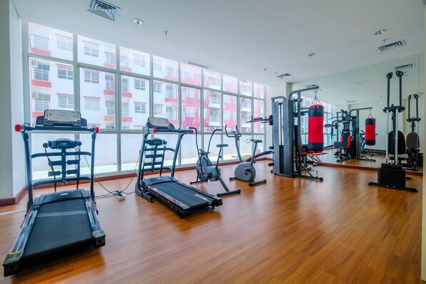 Un gimnasio con cintas de correr, elípticas y equipo de levantamiento de pesas.