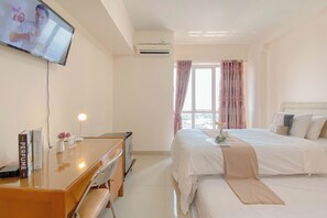 Ein Hotelzimmer mit einem Bett, einem Schreibtisch mit Stuhl, einem an der Wand befestigten Fernseher und einer Klimaanlage.