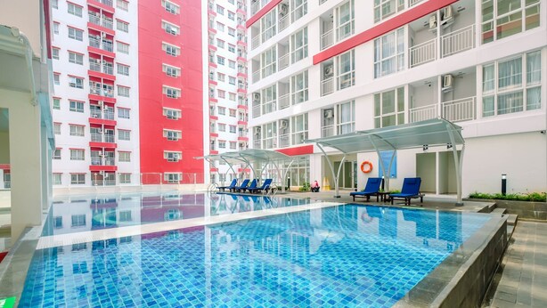 Una piscina interior con azulejos azules, rodeada de sillones de descanso y una zona de estar cubierta.