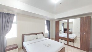 A modern bedroom with a large bed, a wooden wardrobe, and a mirror cabinet. - Serene And Comfort Living 3Br At Podomoro City Deli Medan Apartment (Medan)