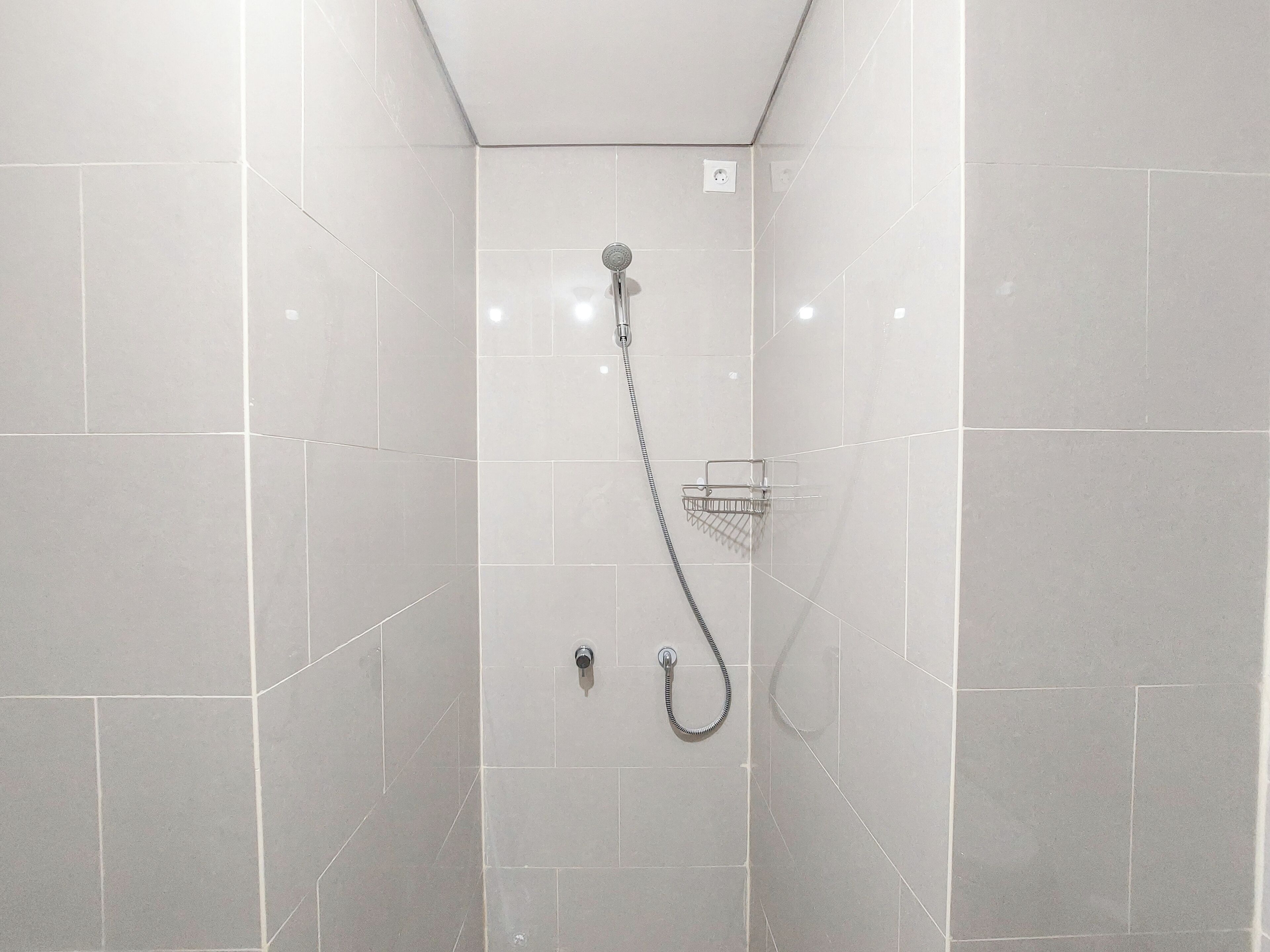 Un espace douche moderne doté d’un pommeau de douche à main, d’un pommeau de douche fixe et d’un robinet mural.