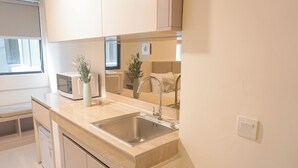 A modern kitchen with a sink, countertop, microwave, and cabinets.