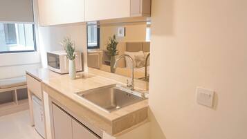 A modern kitchen with a sink, countertop, microwave, and cabinets.