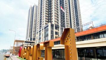 A modern building with a series of golden structures in the foreground, a high-rise building with a flag in the background, and a clear sky.