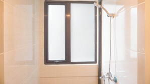 A bathroom with a window, a shower, and tiled walls.