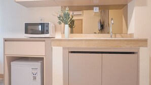 A kitchenette with a microwave, a small refrigerator, a sink, and a vase with flowers.