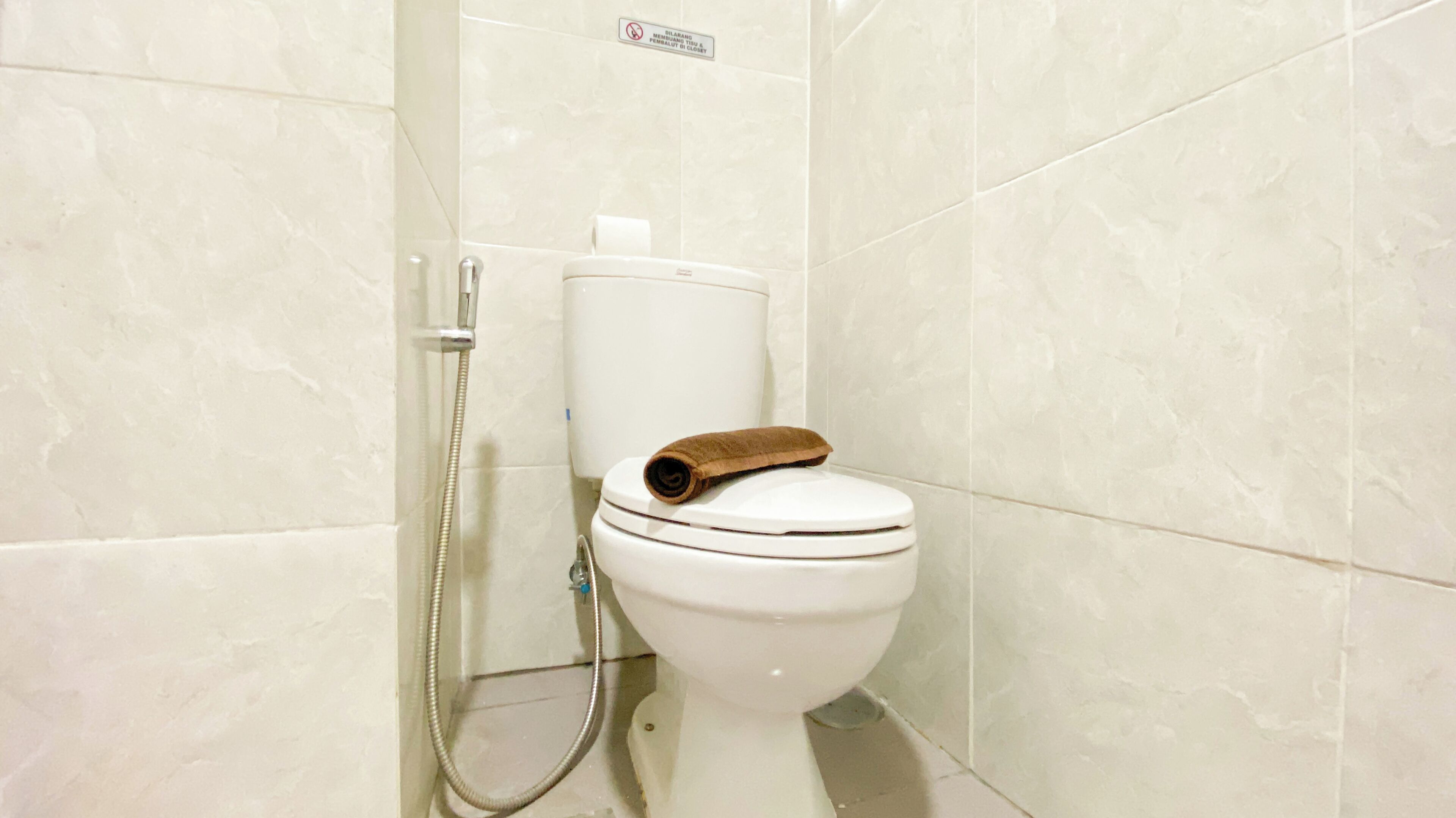A bathroom with a toilet, a shower, and a sign indicating no smoking.