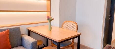 A small, neatly arranged room with a sofa, a wooden table, and a chair.