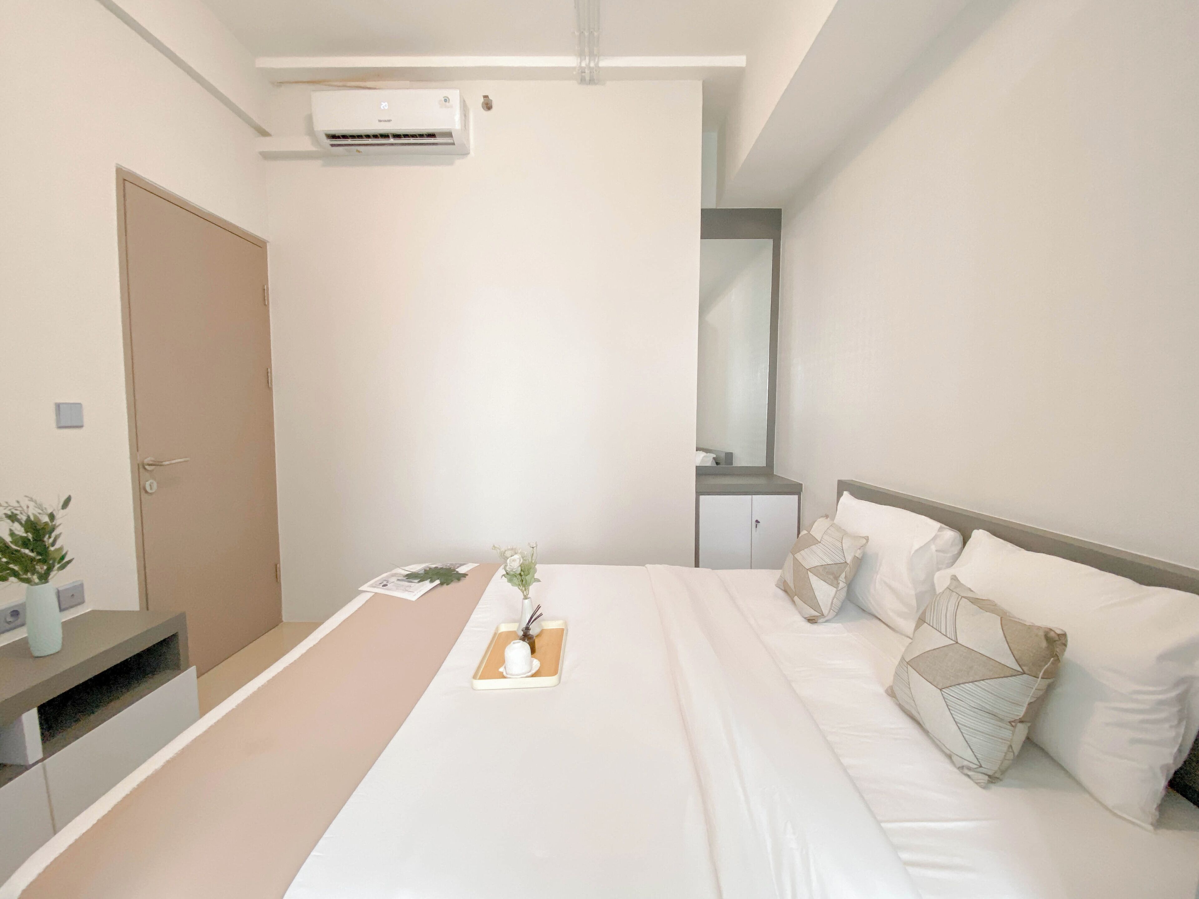 A modern hotel room with a bed, bedside table, and a small desk.