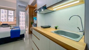 A modern kitchen with a sink, countertop, and wooden cabinets. - Cozy And Enjoy Living Studio Transpark Juanda Bekasi Timur Apartment (Bekasi)