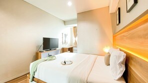 A hotel room with a bed, a TV, a bedside table, and a nightstand.
