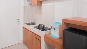 A compact kitchen with a sink, stove, and a water dispenser. - Good And Homey Studio Apartment Urban Heights Residences (South Tangerang)