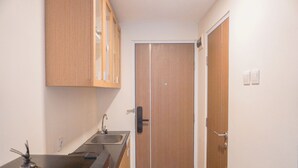 A narrow hallway with a wooden door, a sink, and cabinets.