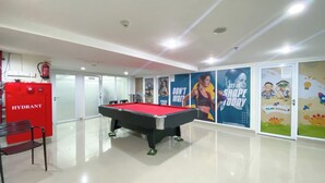 A pool table in a brightly lit room with a red hydrant and a playroom sign.