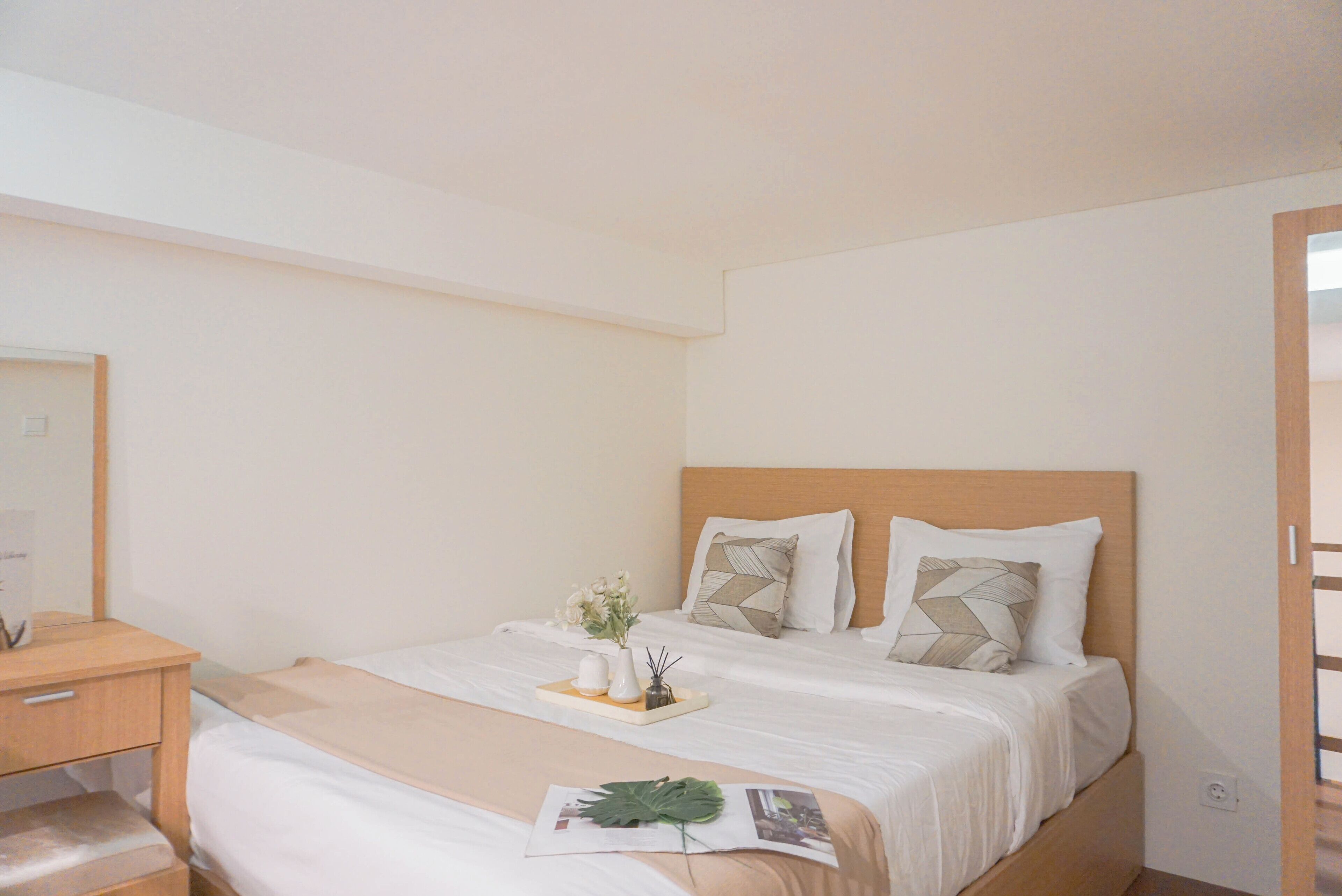 A neatly arranged hotel room with a bed, bedside table, and a small desk.