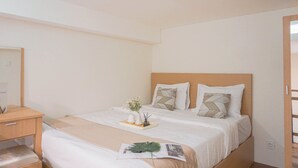A neatly arranged hotel room with a bed, bedside table, and a small desk.