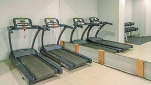 Three treadmills aligned against a wall with a large mirror reflecting the room. - Good Choice Studio Apartment Tamansari Mahogany Karawang (Karawang)