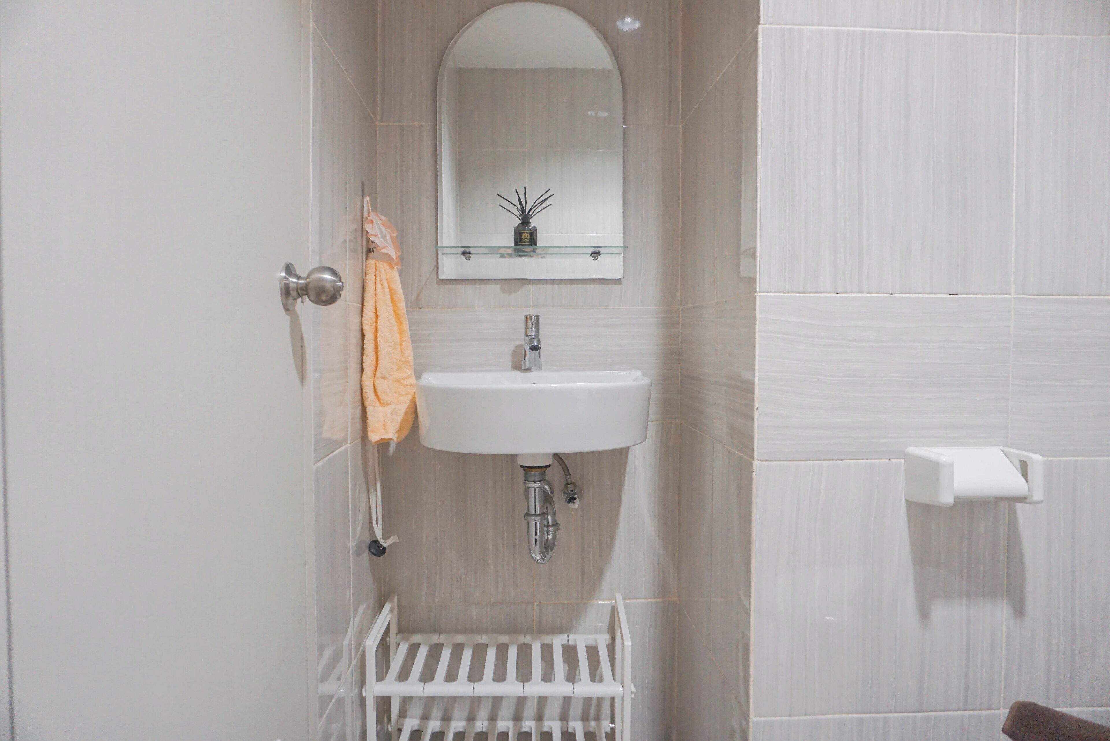 A bathroom with a white sink, a mirror above it, and a towel rack.