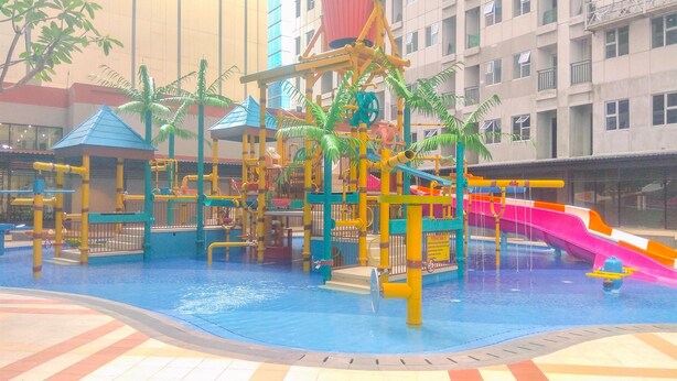 A water play area with slides and climbing structures, surrounded by a pool. - Relaxing Studio Apartment At Transpark Juanda Bekasi Timur (Bekasi)