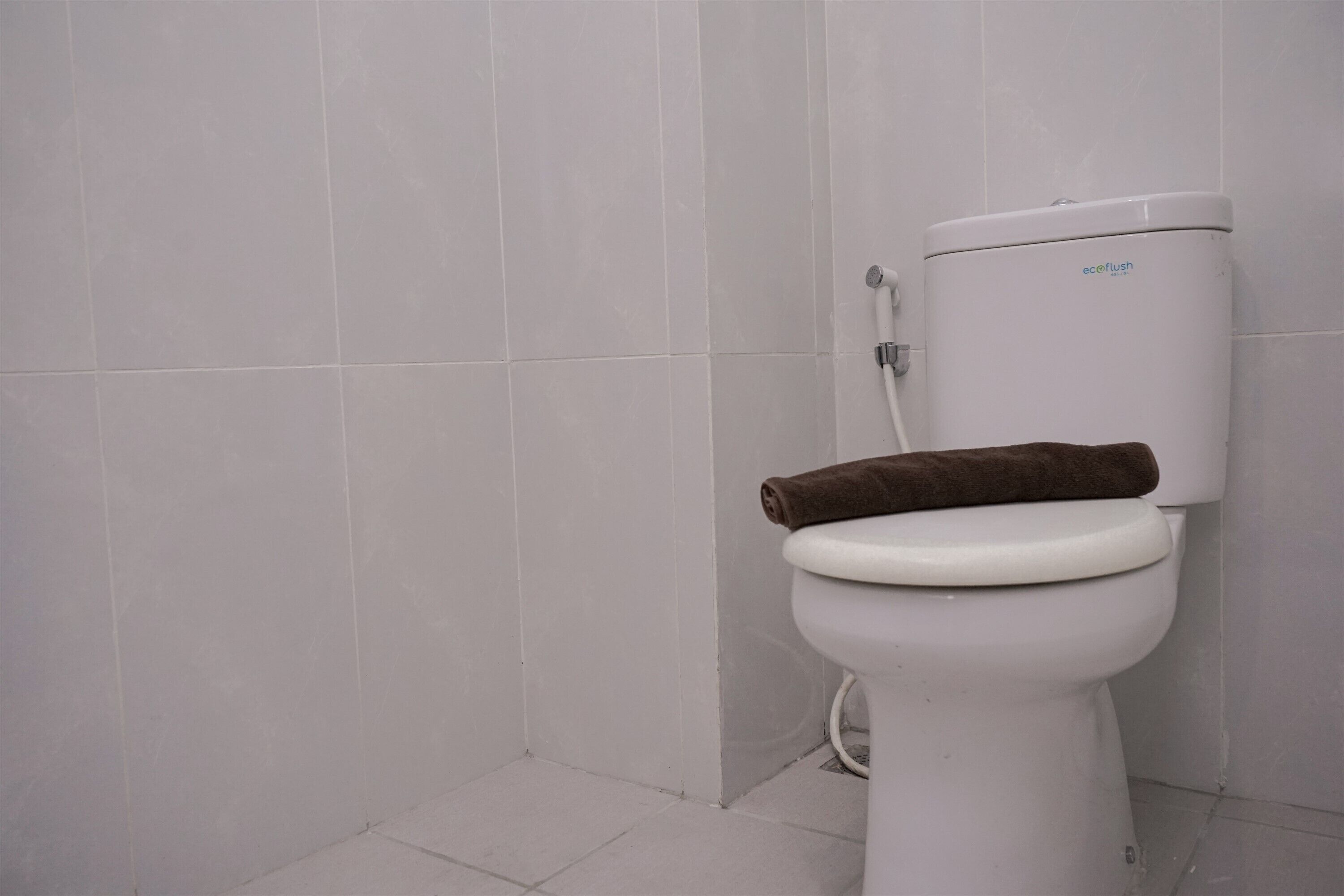 A white toilet with a brown towel on the seat and a white tank.