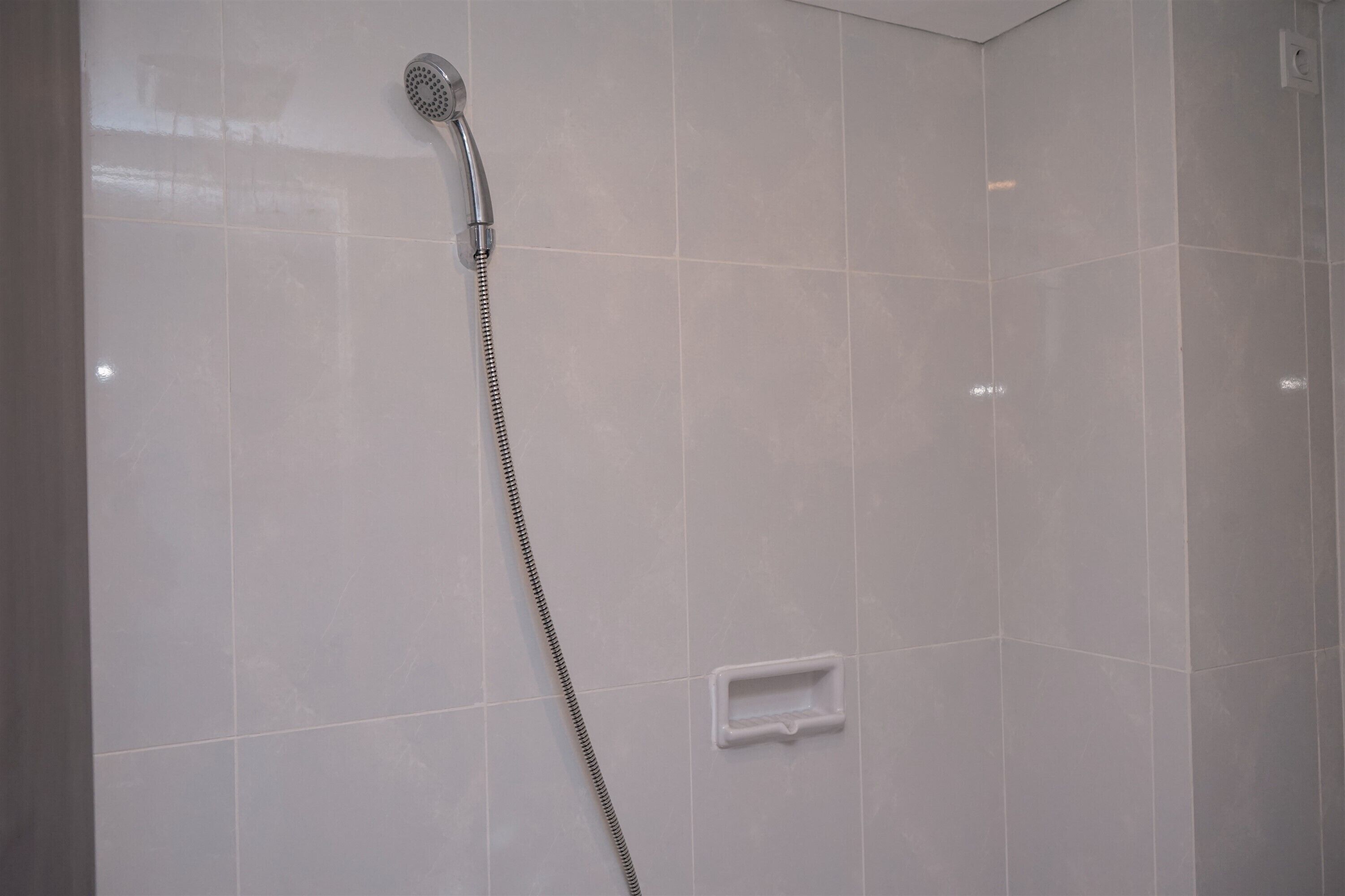 Een douche met een handdouche en bedieningspaneel.