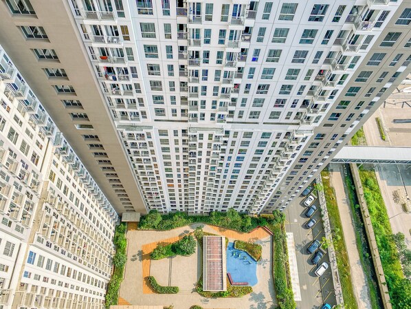 A high-rise residential building with multiple balconies, a rooftop garden, and a swimming pool. - Warm And Good Studio Room At Tokyo Riverside Pik 2 Apartment (Teluknaga)