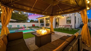 A covered outdoor patio with a fire pit, seating, and a pool. - Luxe Villa • Pool • Spa • Fire Pit • Games & More! (Tampa)