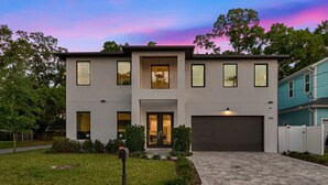 A modern two-story house with a garage, a well-maintained lawn, and a mailbox. - Tampa Modern Oasis • Pool+Spa • Game Room • Sleeps 16 (Tampa)