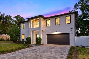 Uma casa moderna de dois andares com garagem, entrada por automóvel e gramado bem cuidado.