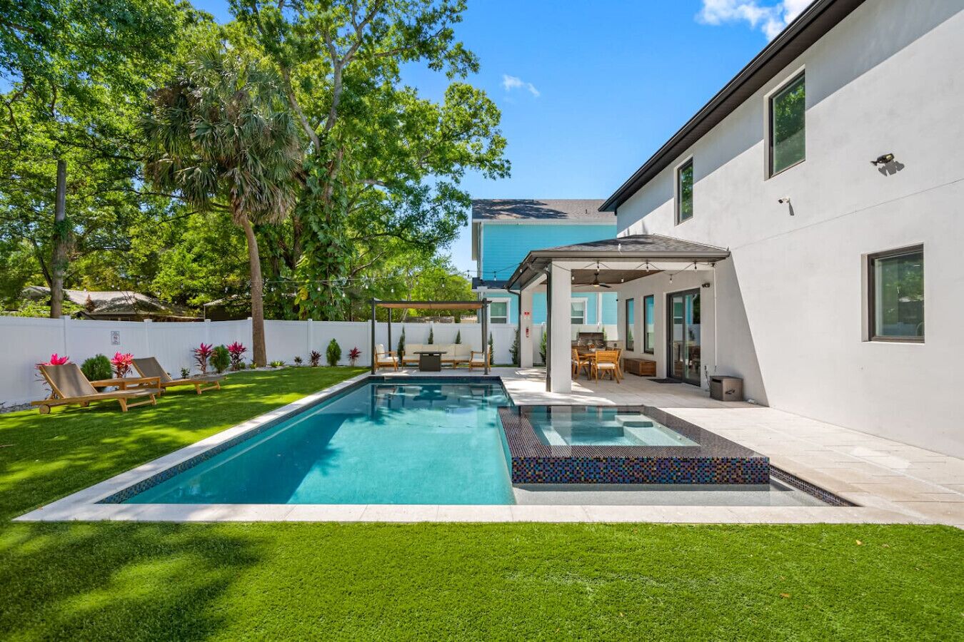 A modern house with a swimming pool, a covered patio, and a well-maintained lawn.