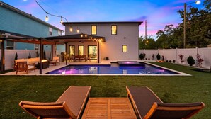 A modern house with a swimming pool, outdoor seating, and string lights. - Tampa Modern Oasis • Pool+Spa • Game Room • Sleeps 16 (Tampa)