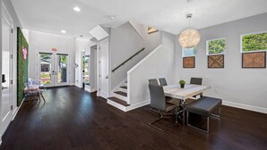 A spacious interior with a dining area, staircase, and a view of the outdoors. - Tampa Modern Oasis • Pool+Spa • Game Room • Sleeps 16 (Tampa)