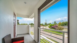 A balcony with a wicker chair, a white railing, and a view of a street and greenery. - Family Oasis • Pool • Slide • Games • Sleeps 14+ (Tampa)