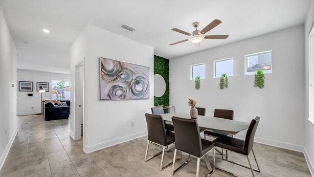 A modern dining area with a round table, six chairs, and a ceiling fan. - Family Oasis • Pool • Slide • Games • Sleeps 14+ (Tampa)