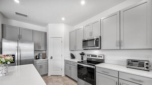 A modern kitchen with stainless steel appliances, grey cabinets, and a white countertop. - Family Oasis • Pool • Slide • Games • Sleeps 14+ (Tampa)