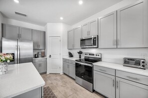 A modern kitchen with stainless steel appliances, grey cabinets, and a white countertop. - Family Oasis • Pool • Slide • Games • Sleeps 14+ (Tampa)