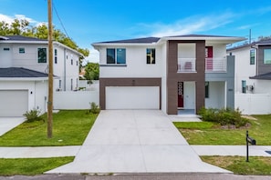 Een modern woonhuis met twee verdiepingen, een garage, een overdekte oprit en een verzorgd gazon.