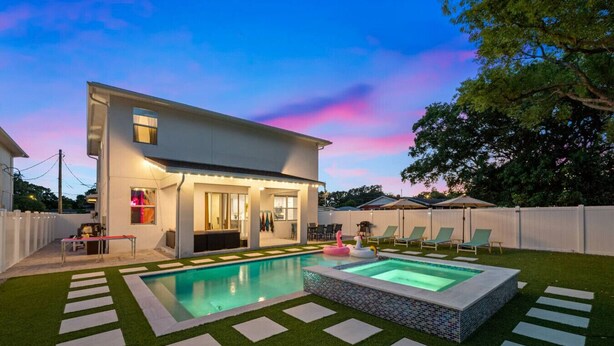 A modern house with a swimming pool, a covered patio, and a well-maintained lawn.
