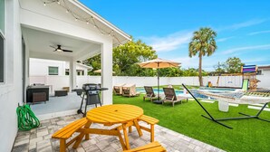 A backyard with a pool, outdoor seating, and a barbecue area.