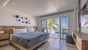 Un dormitorio moderno con una cama grande, cabecera de madera y un balcón con vista al mar.