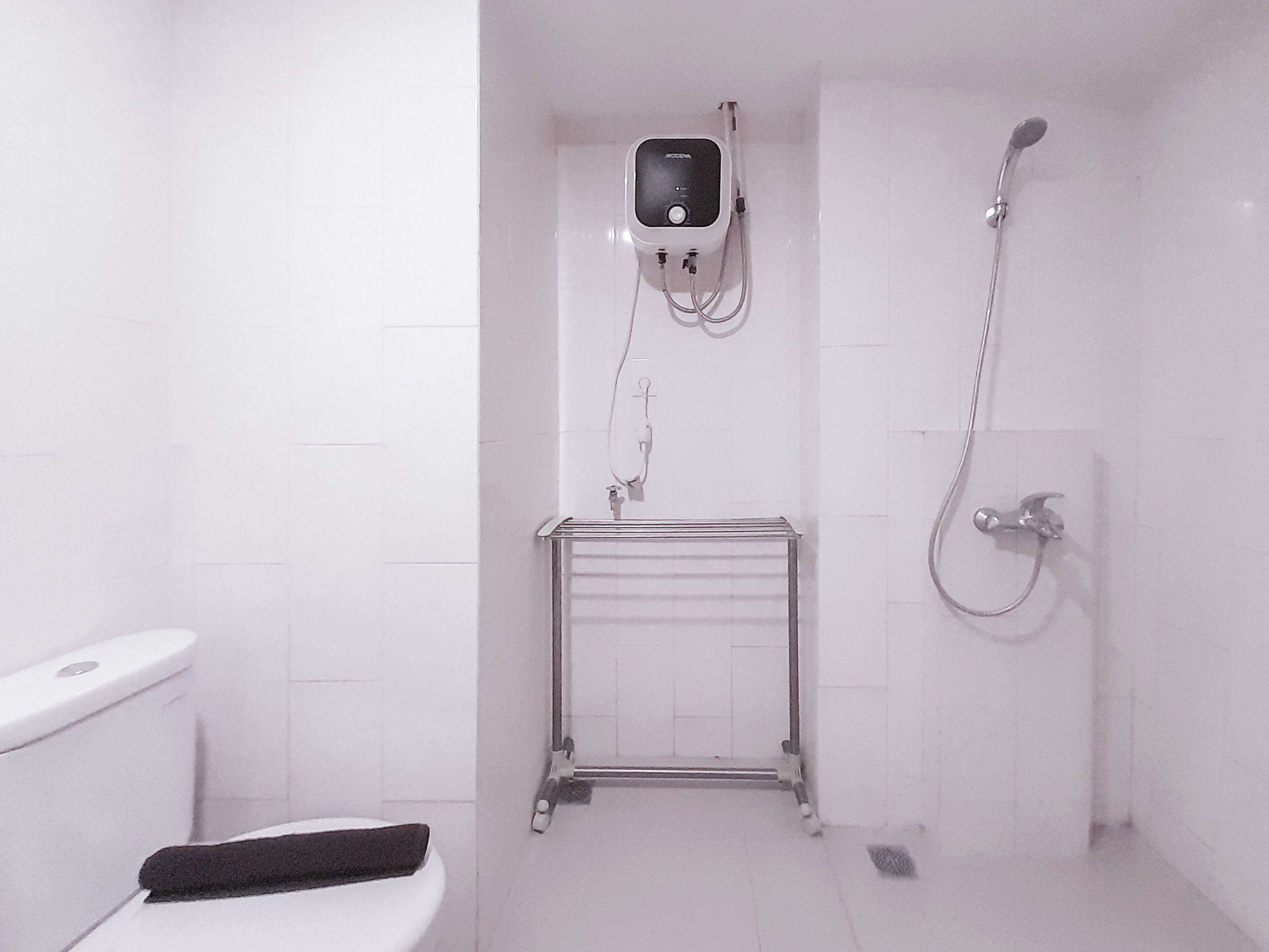 A small, white bathroom with a toilet, a sink, and a shower.