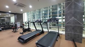 Un gimnasio con cintas de correr, máquinas de pesas y un ventanal grande.