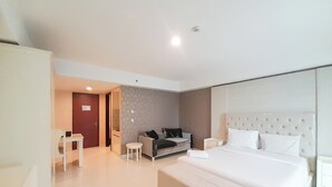 Una habitación de hotel moderna con una cama grande, un sofá, una mesita y un escritorio.