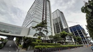 Un edificio moderno con fachada de vidrio y una grúa de construcción al fondo.