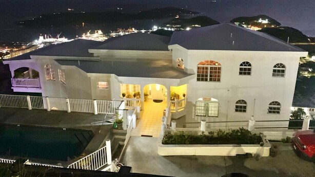 A large, multi-story building with a central courtyard, surrounded by a pool and a red car. - Sleek & Sunny Island Studio | Kitchenette (St. Thomas)