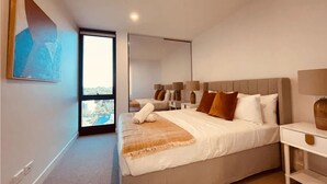 Une chambre moderne avec un grand lit, des tables de chevet, un miroir et une vue sur une piscine.