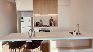 Une cuisine moderne dotée d’un îlot central, de meubles blancs et d’une cuisinière intégrée.