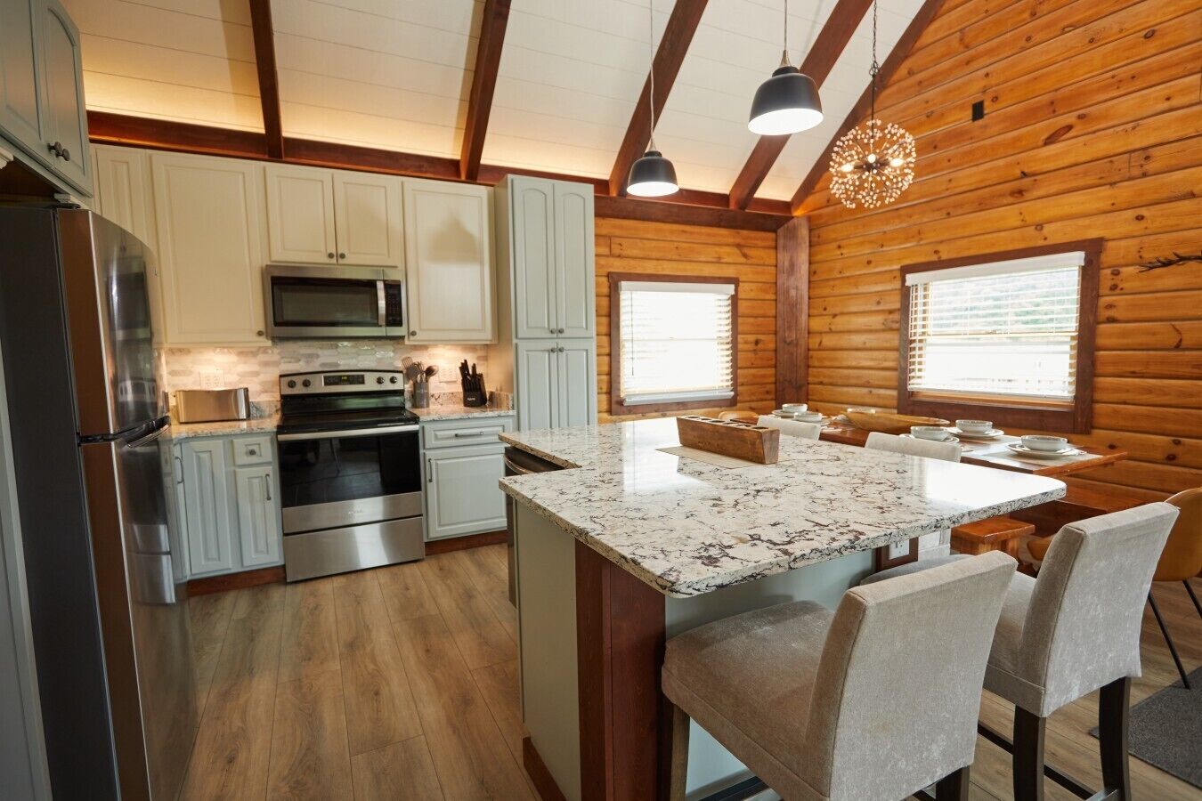A modern kitchen with white cabinets, stainless steel appliances, and a central island with bar stools.