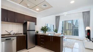 A modern kitchen with dark cabinets, stainless steel appliances, and a large window offering a city view. - Charming 1 Bedroom Marina View (Dubai)